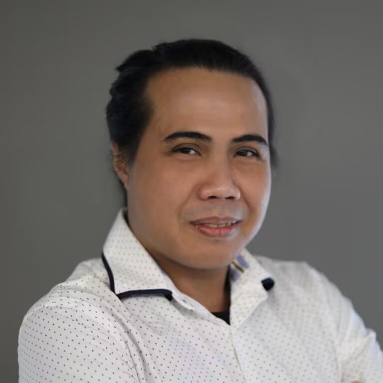 Yassir Yahya in a white shirt against a grey backdrop.